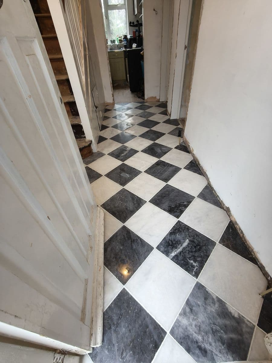 Black and white chequerboard marble-effect tiles laid along a hallway