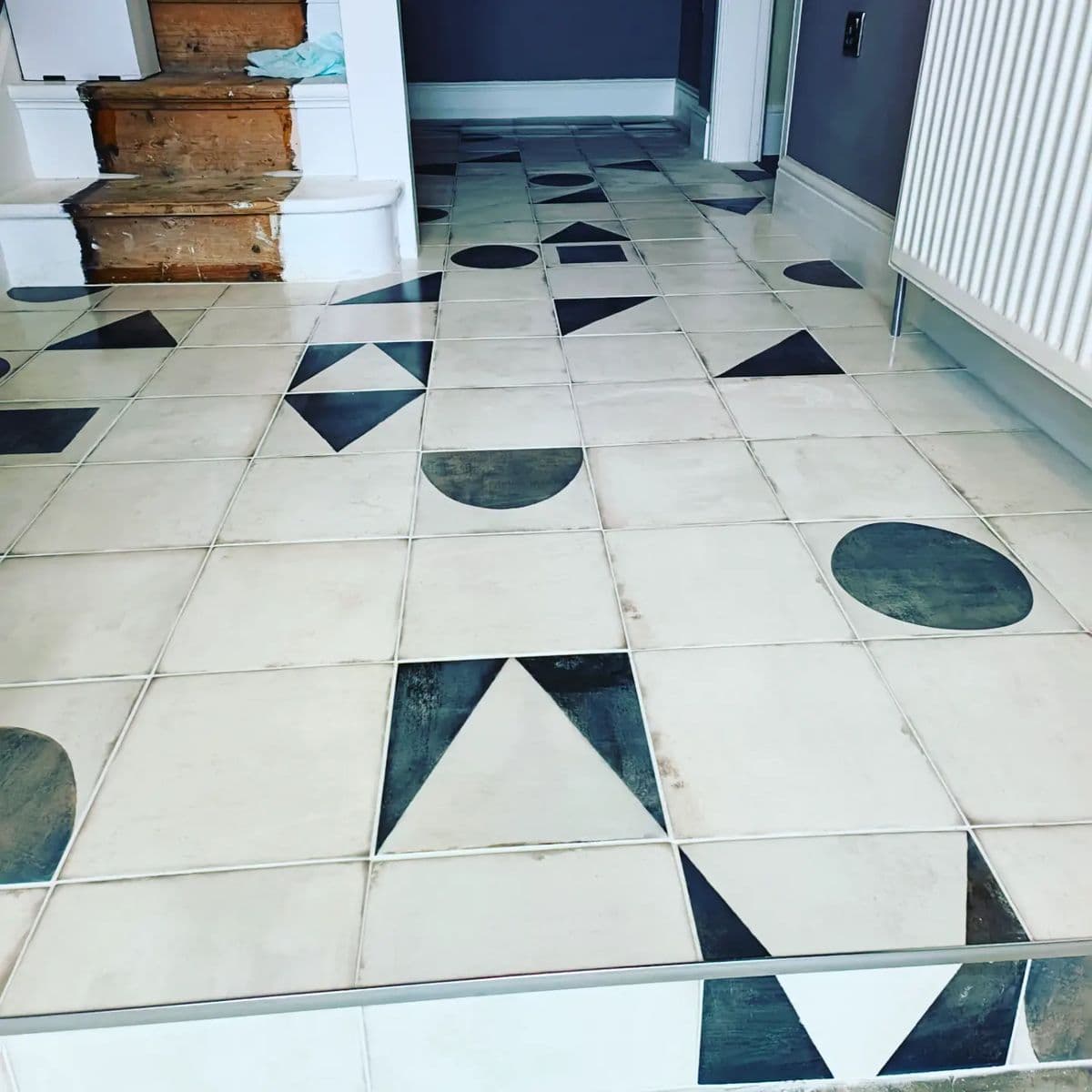 White floor tiles with black triangle and circle patterns in a hallway