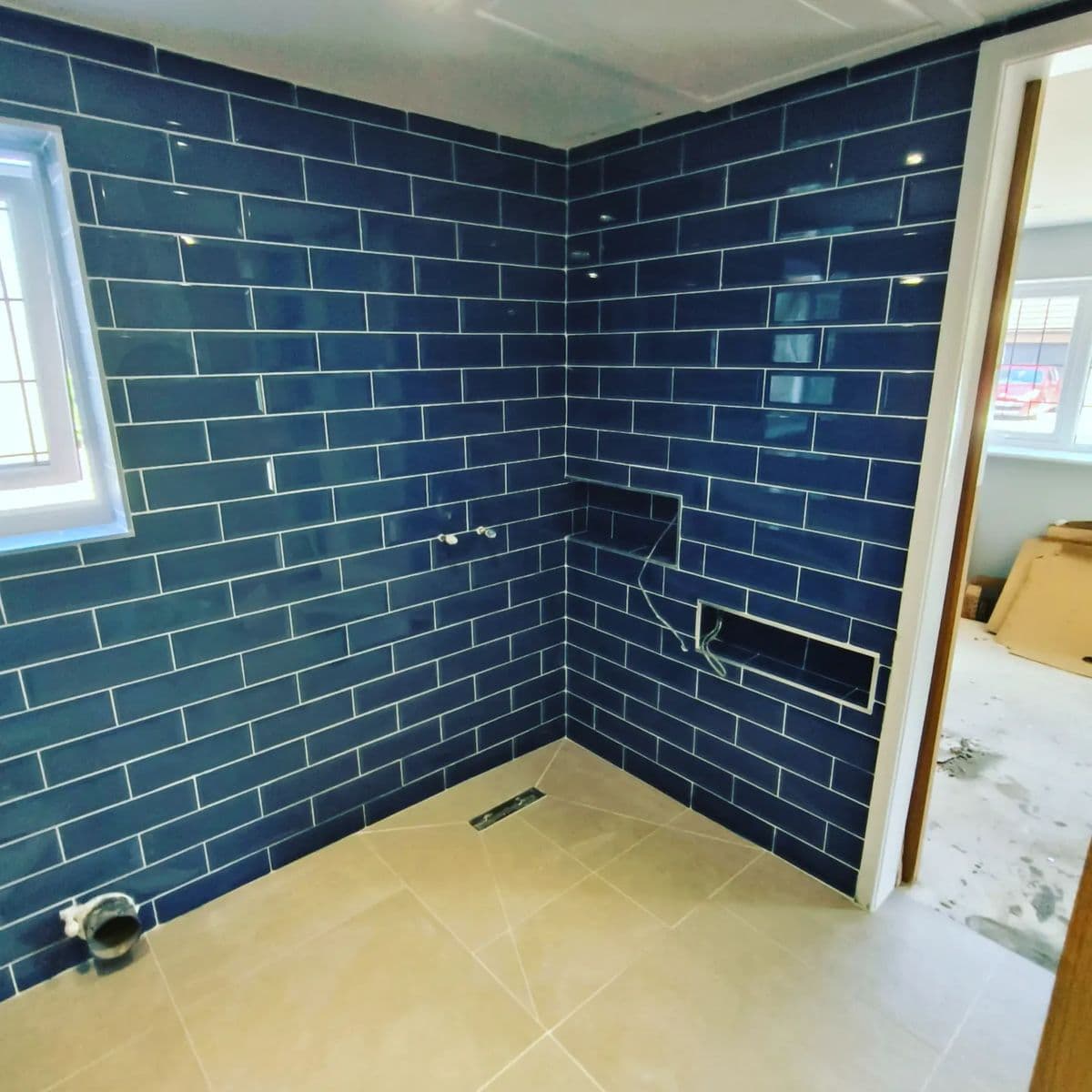 Navy blue gloss metro tiles on the walls of a wet room with a tiled niche