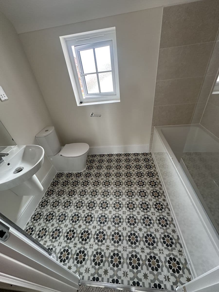 Black and white patterned encaustic-style tiles on a bathroom floor