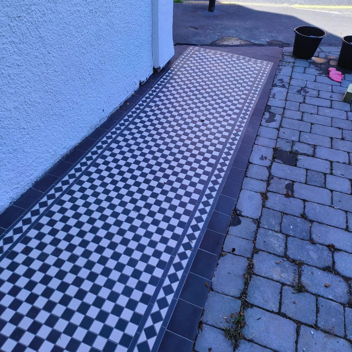 Black and white Victorian-style chequered tiles on an outdoor front path
