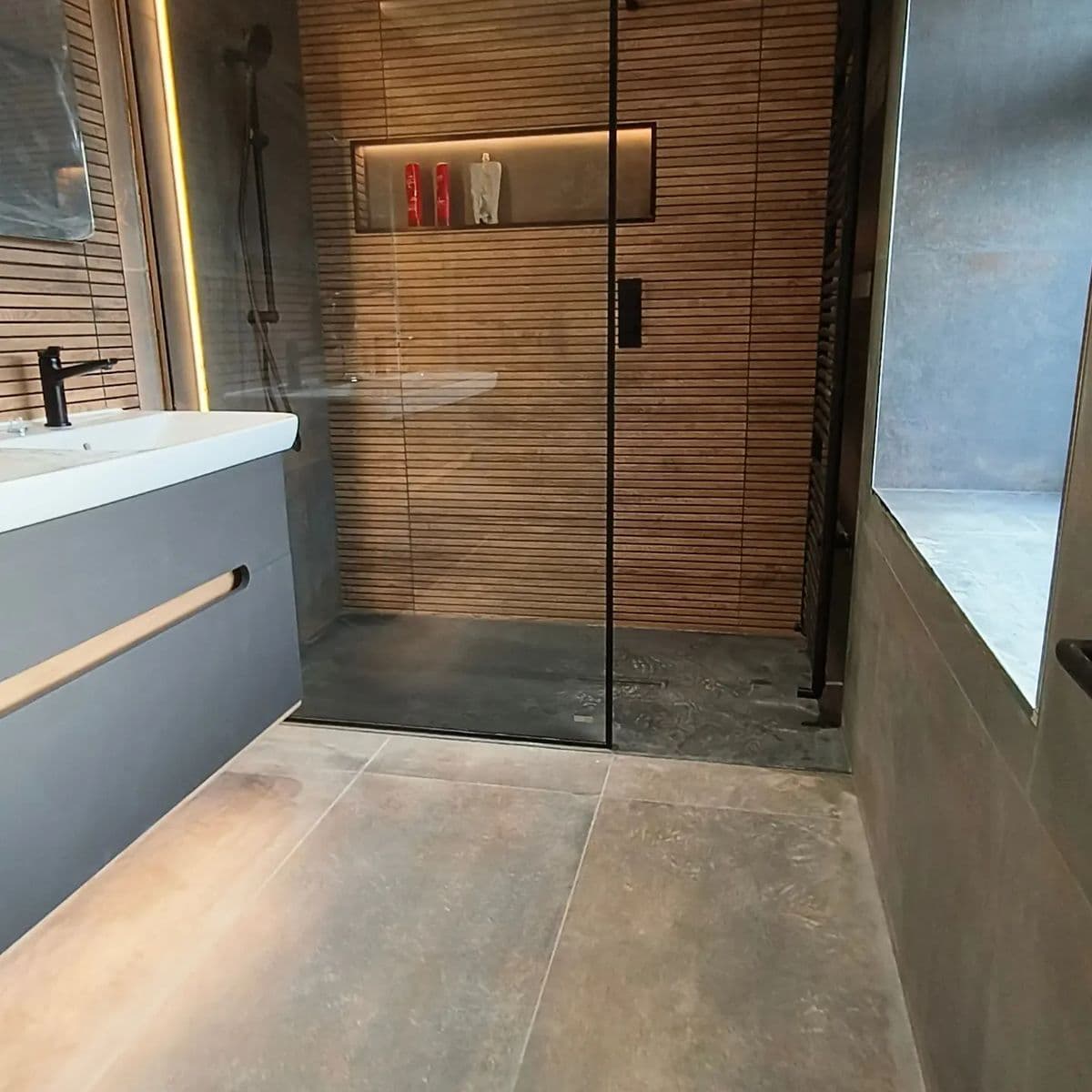 Walk-in wet room shower with a wood-effect slatted tile wall and lit niche