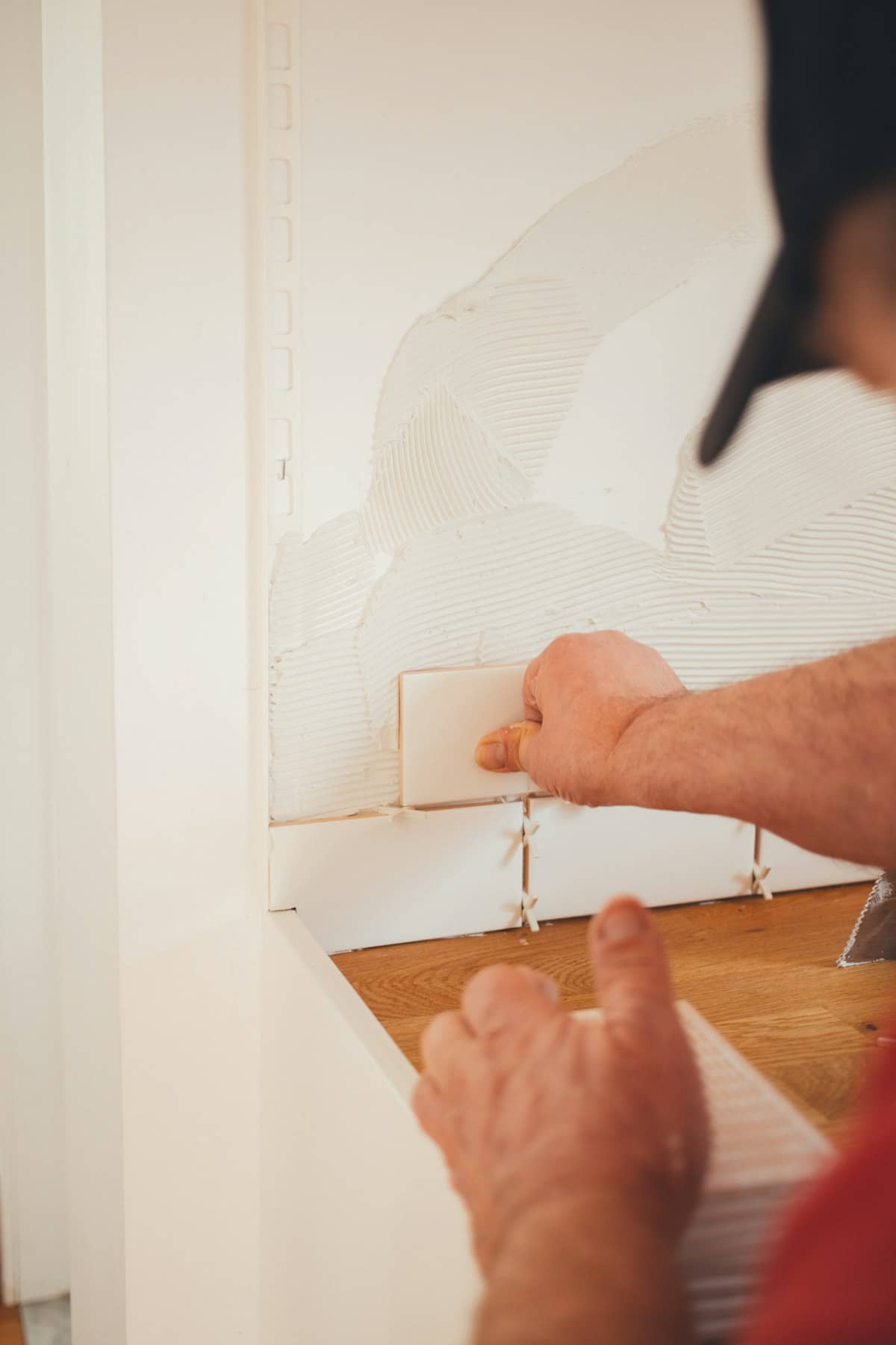 Tiler pressing a white wall tile into place